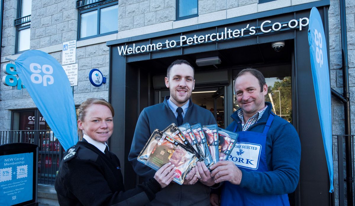 Three people outside a Co-op store holding packs of Scottish pork
